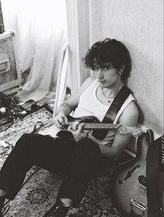 a man sitting on the floor playing an electric guitar