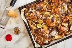 a square casserole dish with chicken and artichokes in it on a marble countertop