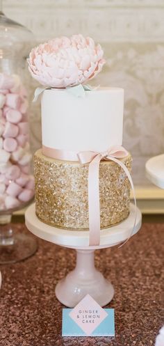 a white and gold wedding cake with pink flowers on top