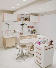 a beauty salon with white furniture and flowers in vases on the counter top next to it