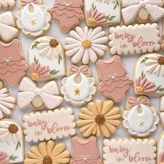 decorated cookies are arranged in rows on a white tablecloth with pink and gold accents