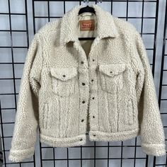 A Relaxed Update On The Classic Trucker Silhouette, This Levi's Jacket Is In Soft Fleece For A Cozy Look And Feel. Cream Color “Sherpa" Or "Teddy" Coat With Buttons. Fits Like A Classic "Jean Jacket" Size: Medium Excellent Condition. No Visible Signs Of Wear. 100% Cotton Sold Out Everywhere Approximate Measurements: Pit To Pit 20" Bottom Width 19 1/2" Length From Back Collar 23" Sleeve Shoulder Seam 22" Self & Lining: 100% Poly Sherpa Front Snap Button Closure Snap Button Flap Pockets And Welt P Levi's Long Sleeve Outerwear With Pockets, Levi's Long Sleeve Outerwear For Fall, Levi's Long Sleeve Fall Outerwear, Levi's Outerwear With Pockets For Fall, Levi's Fleece-lined Winter Outerwear, Levi's Winter Outerwear With Fleece Lining, Winter White Sherpa Outerwear With Pockets, Spring Sherpa Outerwear With Pockets, Casual Winter White Fleece Jacket With Pockets