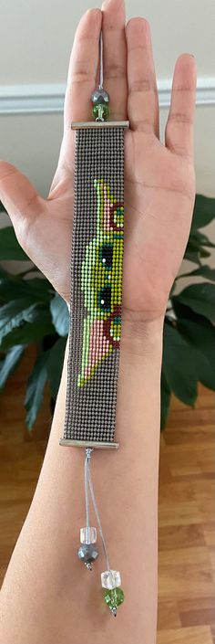 a woman's arm with a beaded bracelet on it that has an image of a cat