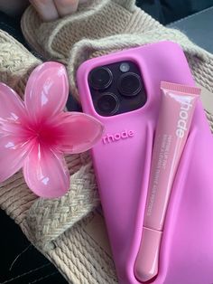 a pink phone case sitting next to a flower