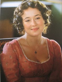 an old photo of a woman in a red dress sitting down and smiling at the camera