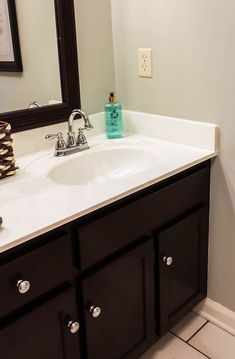 a bathroom with a white sink and black cabinets