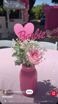 a pink mason jar filled with flowers and heart shaped cutout on top of a table