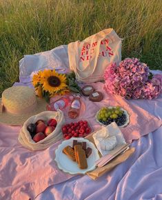 the picnic is set out on the grass with fruit and cheeses, crackers, strawberries