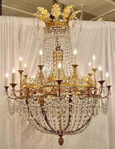 a large chandelier hanging from the ceiling in a room with curtains behind it