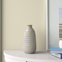 a white vase sitting on top of a table next to a book and coffee cup