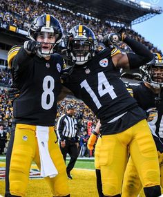 two football players standing next to each other in front of a stadium full of people