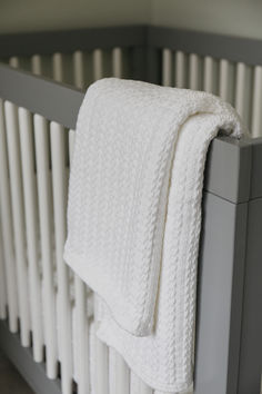 a white blanket sitting on top of a crib