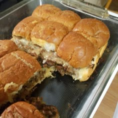 several sliders cut in half sitting on top of a metal pan next to each other