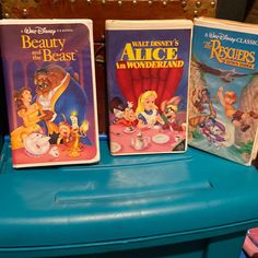 three disney dvd's sitting on top of a blue table