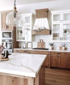 a kitchen with wooden cabinets and white marble counter tops, an island in the middle