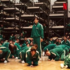 a group of people sitting on the floor in front of some stairs with one person standing