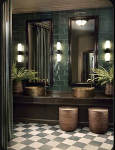 a bathroom with checkered flooring and green tile on the walls, along with two large mirrors