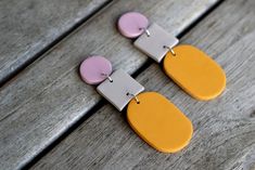 two yellow and pink earrings sitting on top of a wooden table