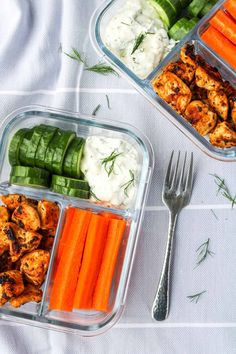 two plastic containers filled with chicken, carrots and celery next to a fork