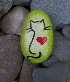 a painted rock with a cat's face on it and a heart in the middle