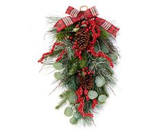 a christmas wreath with pine cones, berries and greenery is hanging on the wall