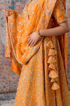 Channelize your desi vibes with adorable Apricot coloured Lehenga. A fashion-savvy lady who resides in our body will never compromise with our looks at any cost. Lehenga is always the perfect sartorial choice for all women when it comes to attending a wedding. Keeping in mind your style statement, we have designed this beautiful apricot-coloured lehenga for our pretty ladies. This lehenga is made from raw silk material and embroidered with zardozi, sequins, and dabka. It is the perfect attire fo Designer Orange Palazzo Set With Zari Work, Orange Designer Palazzo Set For Navratri, Orange Palazzo Set With Dupatta And Traditional Drape, Traditional Drape Orange Palazzo Set With Dupatta, Festive Designer Orange Sharara, Festive Orange Designer Sharara, Orange Dori Work Sharara, Designer Orange Sharara With Zari Work, Semi-stitched Orange Palazzo Set With Zari Work