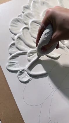 someone is drawing on the paper with white paint and glues to make it look like a flower