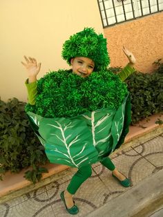 a woman dressed as a leafy plant with her hands in the air