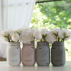 four painted mason jars with flowers in them