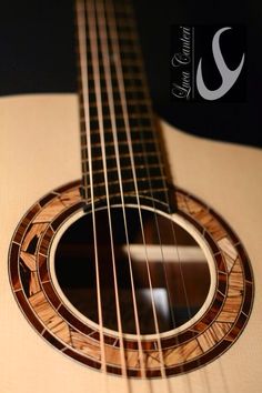 a close up of an acoustic guitar with the strings and frets showing, on a black background