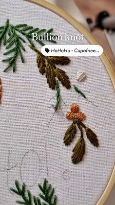 a close up of a embroidery on a piece of cloth with leaves and flowers in it