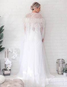 "It isn't enough to have feathers, you must dare to fly...." Add a touch of glamour to your bridal gown with this stunning Floor Length Tulle Beaded Cape with Ostrich Feather is a striking ivory color. With it’s floor length style, this ostrich feather statement piece is ideal for brides who are wanting something fabulous and show stopping on their wedding day. Hand Dyed Luxurious Ostrich Feather Cape Veil Clear Snap front closure Floor length style design with rounded front Made from Ethically Elegant Feather-trim Wedding Gown, Elegant Wedding Gown With Feather Trim, Elegant Wedding Gown With Feathers, White Feathered Dresses For Wedding, White Ostrich Feather Wedding Dress, Cape Veil, Feather Cape, Beaded Cape, Ostrich Feather