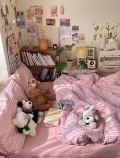 there are stuffed animals on the bed in this small room with pink sheets and pillows