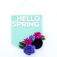 there is a sign that says hello spring with flowers hanging from the side of it