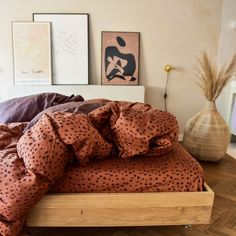 an unmade bed with brown and black polka dot sheets on it, in a bedroom