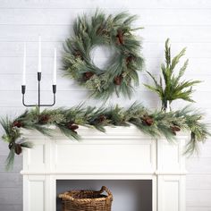 a mantel decorated with pine cones and greenery, candles and wreath on the mantle