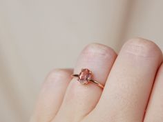 a woman's hand holding a pink diamond ring