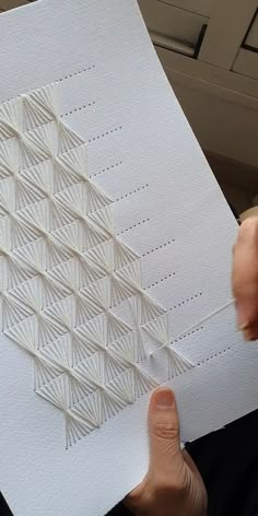 a person holding up a piece of paper that has been made into an intricate pattern