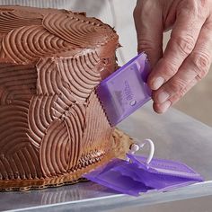 a person is cutting into a cake with purple icing and plastic cutters on it