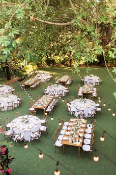 an outdoor dining area with tables and chairs set up for a formal dinner in the woods