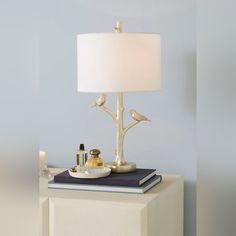 a table lamp sitting on top of a book next to a white vase and candle