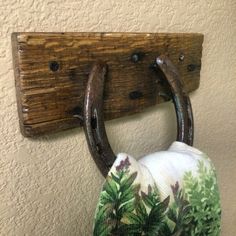 a pair of horseshoes hanging from a wooden hook on a wall next to a potted plant