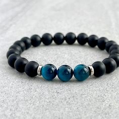 Men's beaded bracelet features: ~ 6mm, 8mm or 10mm matte onyx beads ~ 6mm, 8mm or 10mm aqua blue tiger eye beads ~ 4mm, 6mm or 8mm stainless steel spacers ~ Stretchy cord; simply slide bracelet on and off wrist ~ Comes packaged in a re-usable microfiber pouch To ensure the perfect fit, please use the bracelet sizing instructions found in the photo gallery. Mens Gemstone Jewelry, Male Bead Bracelet, Men’s Beaded Bracelets Diy, Men’s Beaded Jewelry, Stone Bracelet For Men, Men Beads Bracelet, Male Beaded Bracelets, Men Beaded Bracelet Ideas, Diy Bracelets For Men