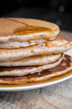 stack of pancakes covered in syrup on top of a white plate