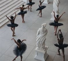 ballet students in tutus and leotards standing around a statue