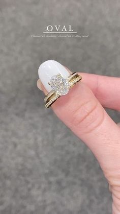 a woman's hand with two gold rings on top of her finger and an oval shaped diamond in the middle