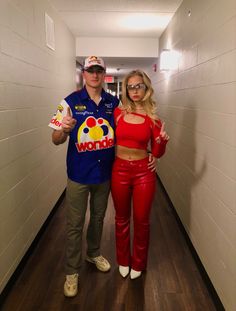 a man and woman in red outfits standing next to each other on a long hallway