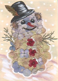 a snowman made out of flowers and leaves with a hat on it's head