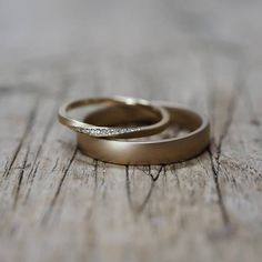 two gold wedding rings sitting on top of a wooden table