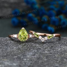 an engagement ring with two pear shaped green and white diamonds on top of a rock